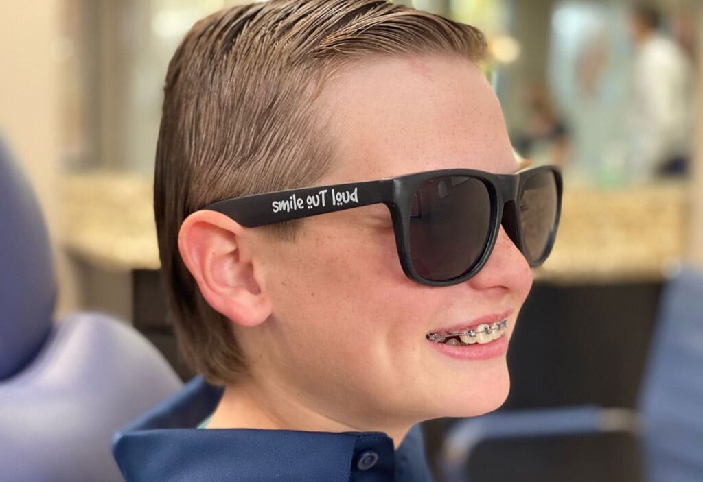 Boy wearing sunglasses and smiling | Harwell & Cook Orthodontics