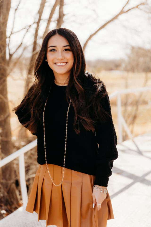 A smiling woman in a black sweater | Harwell & Cook Orthodontics
