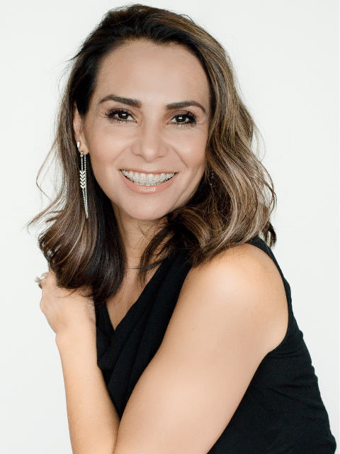 A smiling woman in a black top | Harwell & Cook Orthodontics