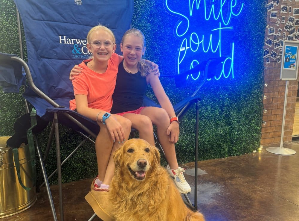 Two women and a dog posing outdoors. | Harwell & Cook Orthodontics