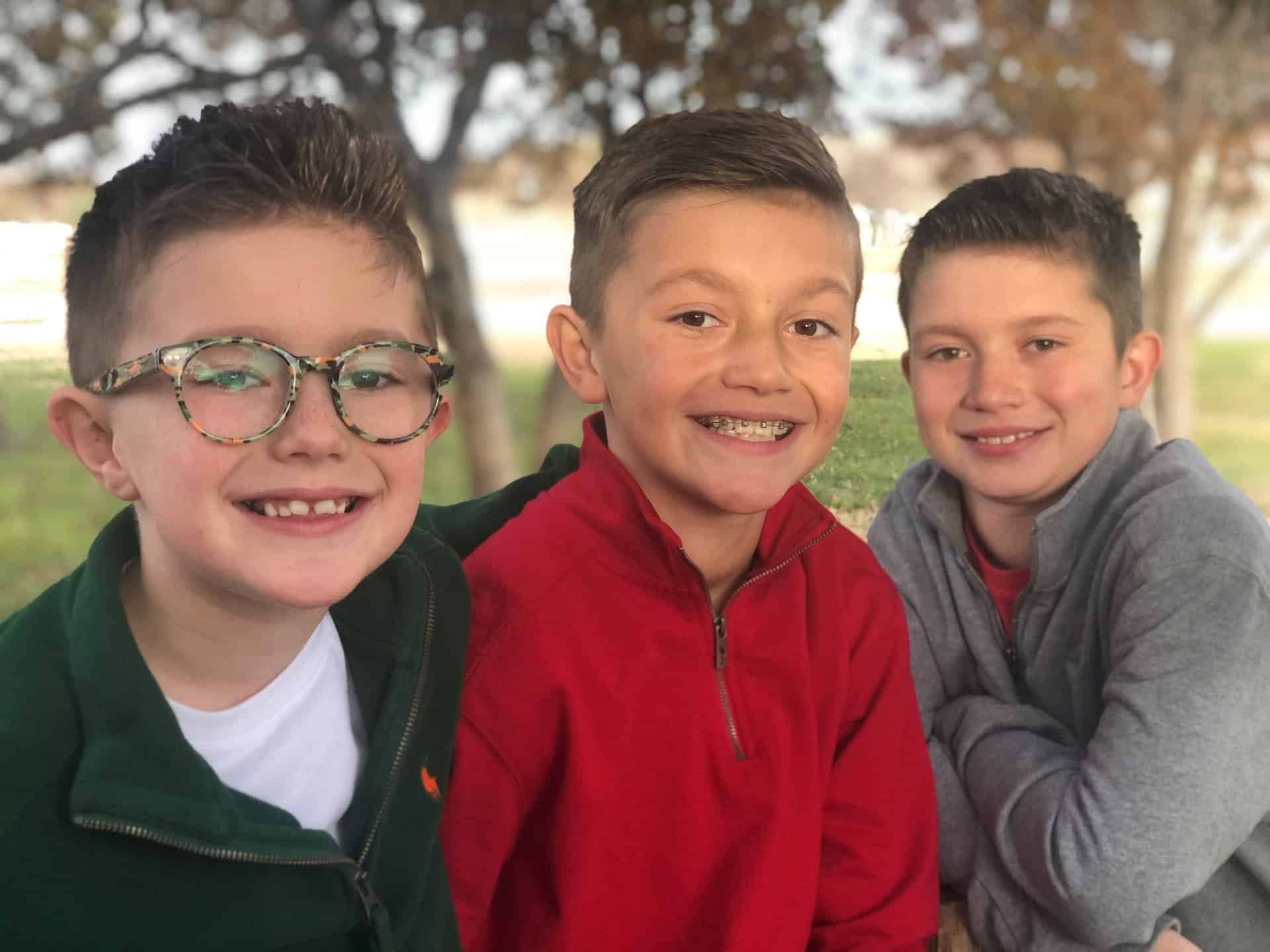 three smiling boys posing together. | Harwell & Cook Orthodontics
