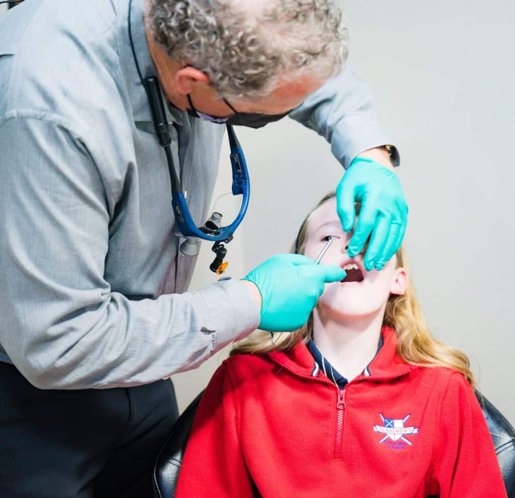 A doctor using dental tools on a child patient. | Harwell & Cook Orthodontics