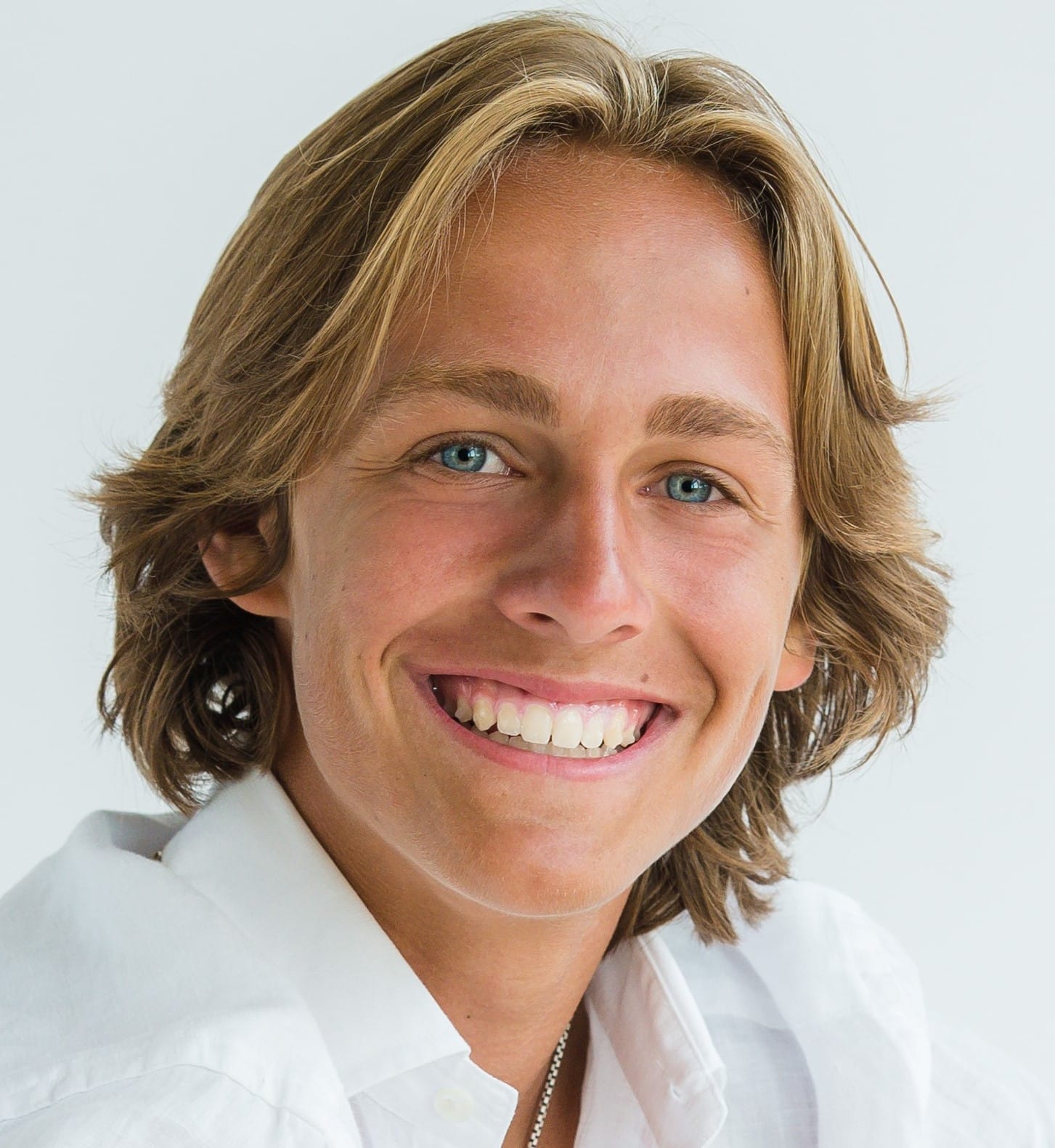 A smiling man with long hair. | Harwell & Cook Orthodontics