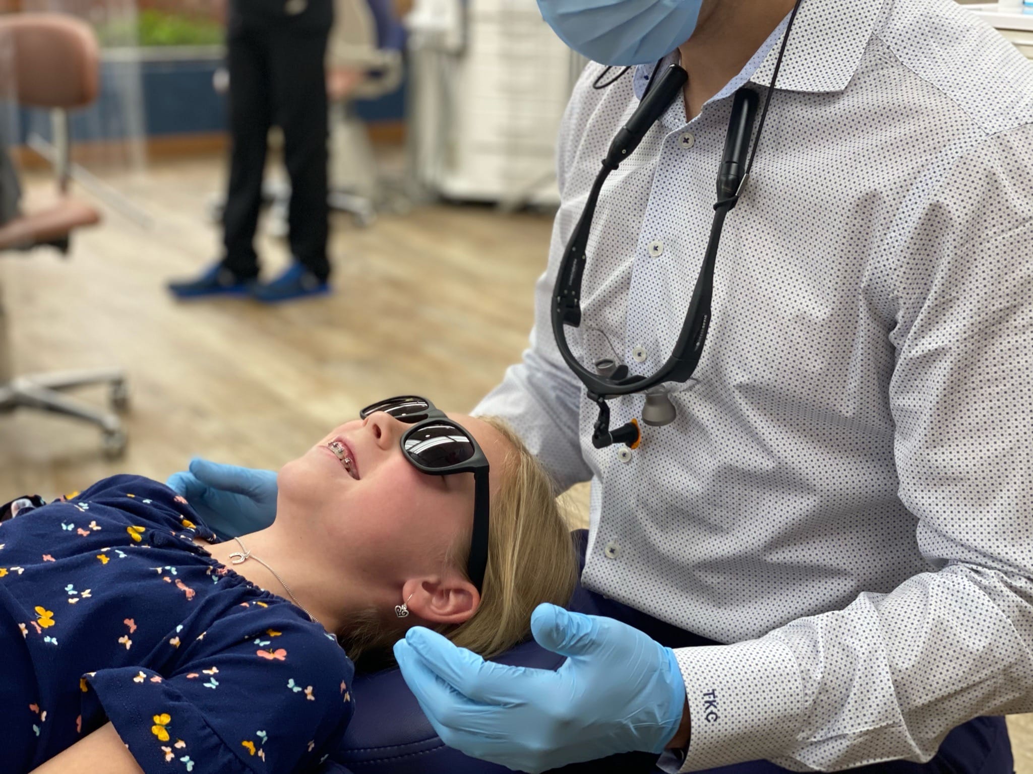 A doctor in sunglasses working on a patient. | Harwell & Cook Orthodontics